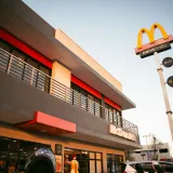A modern McDonald's fast food restaurant with distinctive branding and drive-thru facilities under a clear blue sky.