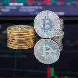 Bitcoin coins stacked in front of cryptocurrency trading chart reflecting market trends.