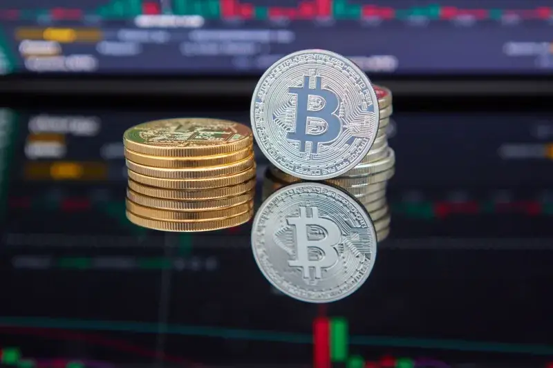 Bitcoin coins stacked in front of cryptocurrency trading chart reflecting market trends.