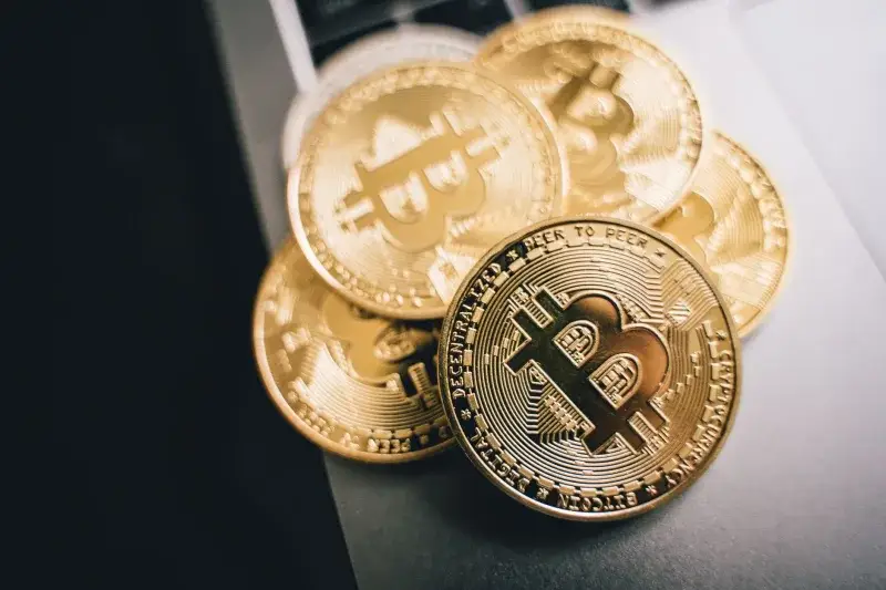 Close-up of golden Bitcoin coins on a laptop keyboard, symbolizing cryptocurrency investment.