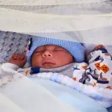 Close-up of a peacefully sleeping newborn baby in a cozy crib, wrapped in a soft blanket.
