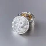 Close-up of shiny Bitcoin cryptocurrency coins with a reflective surface on a gray background.