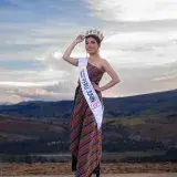 Elegant Miss Junín in a traditional dress and crown, set against a scenic sunset in Junín, Peru.