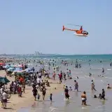 A lively day at Miramar Beach, Ciudad Madero, Mexico with a helicopter flying over beachgoers.