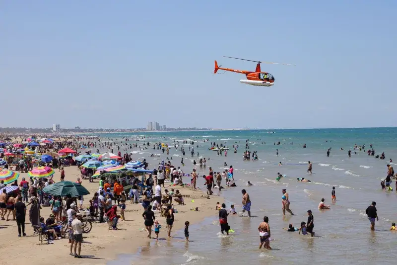 A lively day at Miramar Beach, Ciudad Madero, Mexico with a helicopter flying over beachgoers.