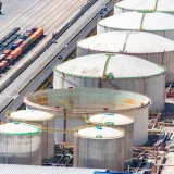 Aerial shot of large oil storage tanks in an industrial district with adjacent railway tracks.