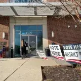 Woman enters a polling location inside a mall to cast a ballot in the November 8, 2022 midterm election while two other women examine a ballot drop box.