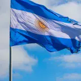 The national flag of Argentina waving against a bright blue sky, showcasing its vibrant colors.