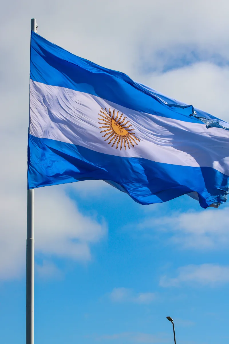 The national flag of Argentina waving against a bright blue sky, showcasing its vibrant colors.