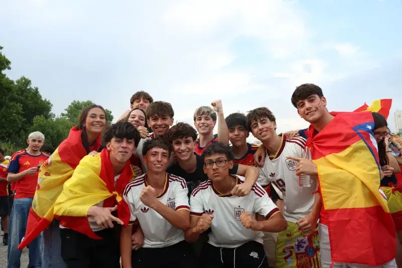 A group of enthusiastic Spanish football fans celebrating outdoors in Madrid.