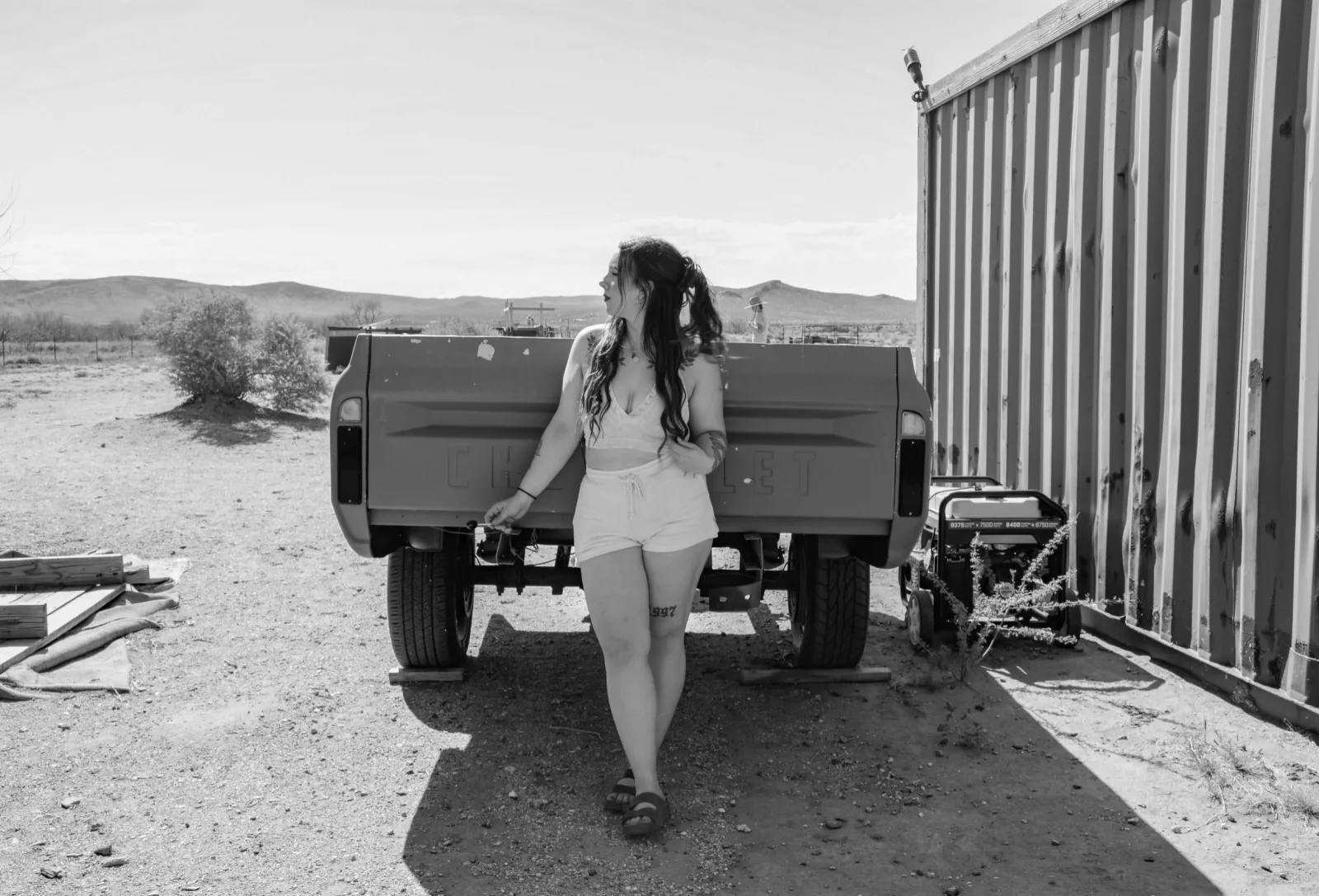 Black and white image of a woman by a trailer in Dolan Springs, AZ.