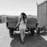 Black and white image of a woman by a trailer in Dolan Springs, AZ.