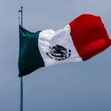 The Mexican flag proudly waves against a clear blue sky in Ciudad de México, showcasing its national symbol.