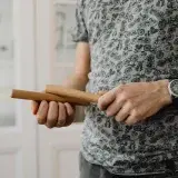 Detailed view of a person holding wooden claves, showcasing the instrument.