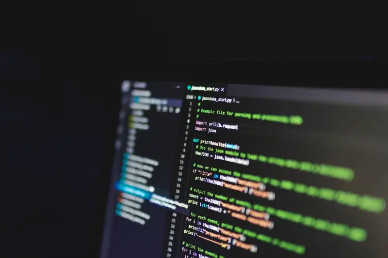 Programming code on a computer screen in a dark room, showcasing technology and IT expertise.