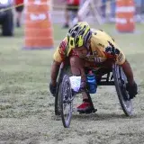 Determined wheelchair racer competing in an outdoor marathon, displaying focus and athleticism.
