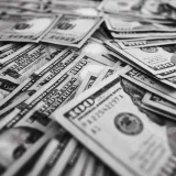 Monochrome image of scattered US hundred dollar bills representing wealth and prosperity.
