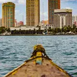 Scenic view of Maracaibo's skyline from a boat on the lake, showcasing tall buildings and a clear day.