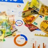Colorful Euro and Romanian Lei banknotes on top of financial charts, symbolizing currency exchange and economic analysis.