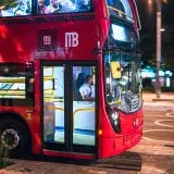 A vibrant red city bus transporting passengers at night in Ciudad de México.