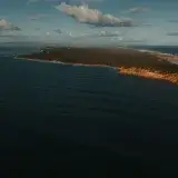 A breathtaking aerial view of the rugged coastline of Portsea, Victoria, Australia, bathed in sunlight.