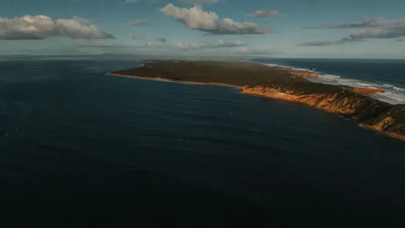 A breathtaking aerial view of the rugged coastline of Portsea, Victoria, Australia, bathed in sunlight.