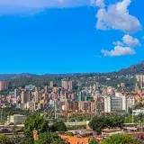 A stunning view of Medellín, Colombia with a backdrop of mountains and clear blue skies.