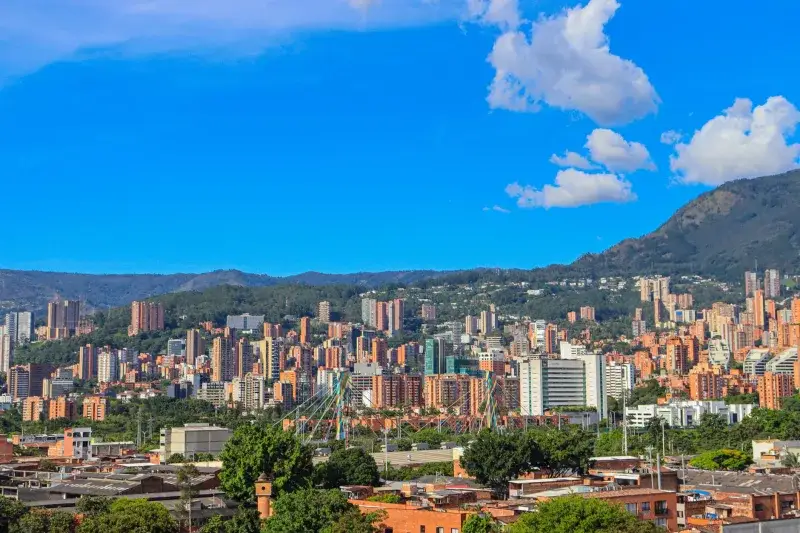 A stunning view of Medellín, Colombia with a backdrop of mountains and clear blue skies.