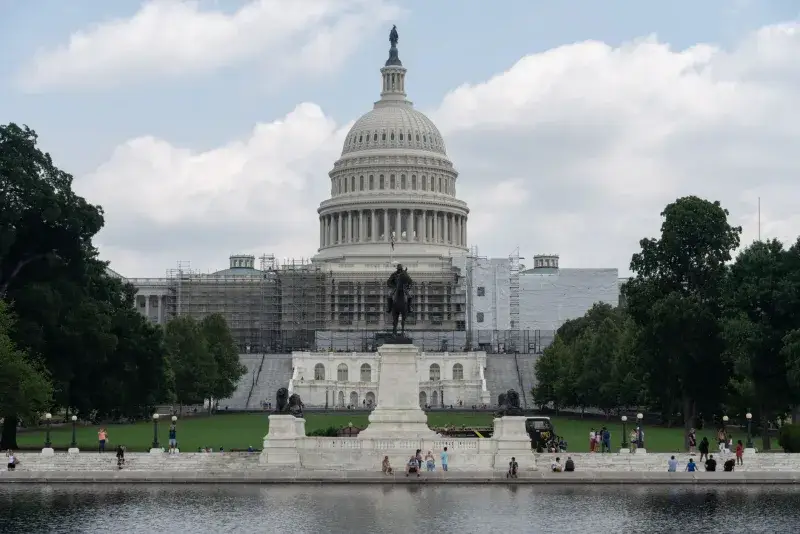 US Capitol with dome, statue, and reflecting pool on a sunny day in Washington, D.C.