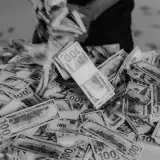 A large pile of hundred dollar bills being handled, creating a sense of wealth and abundance.