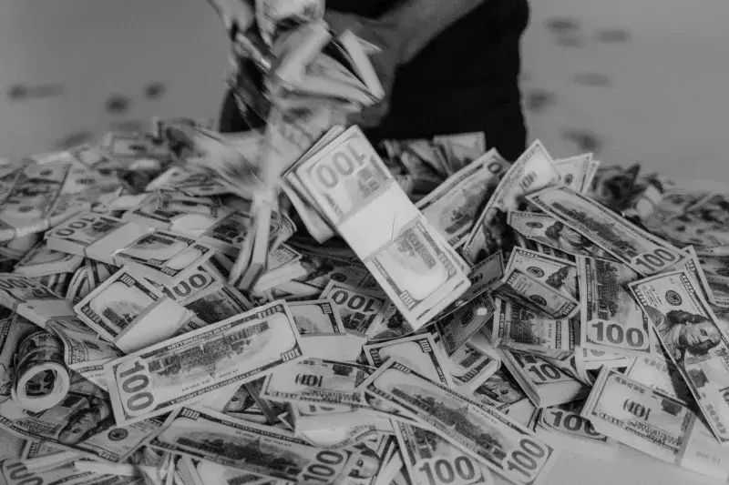 A large pile of hundred dollar bills being handled, creating a sense of wealth and abundance.