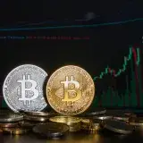 Golden and silver Bitcoin coins against a financial graph display, highlighting cryptocurrency investment trends.