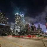 Vibrant night view of downtown Los Angeles with illuminated skyscrapers and light trails.