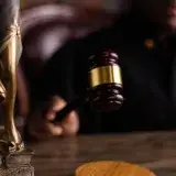 Close-up of a judge holding a gavel, symbolizing justice and law in a courtroom setting.