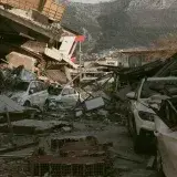 Severe earthquake damage in Antakya, Türkiye, with collapsed buildings and cars.