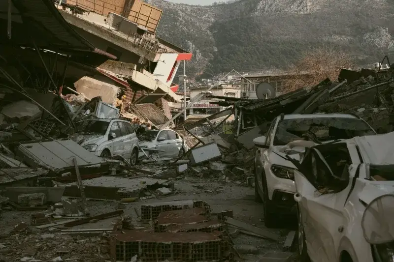 Severe earthquake damage in Antakya, Türkiye, with collapsed buildings and cars.