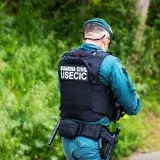 Guardia Civil officer in uniform walking in a natural setting.