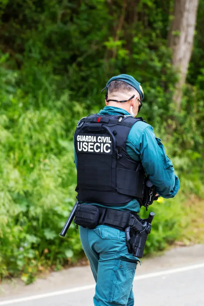 Guardia Civil officer in uniform walking in a natural setting.