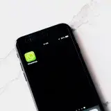 Imagen de primer plano de un smartphone mostrando WhatsApp sobre una mesa blanca.