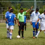 Soccer players and referee on a green field in Venezuela, mid-game action.