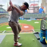 Man practicing golf swing at a baseball stadium golf range in Cleveland.