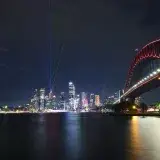 Vivid night view of Sydney Harbour featuring the illuminated Opera House, CBD skyline, and Harbour Bridge.