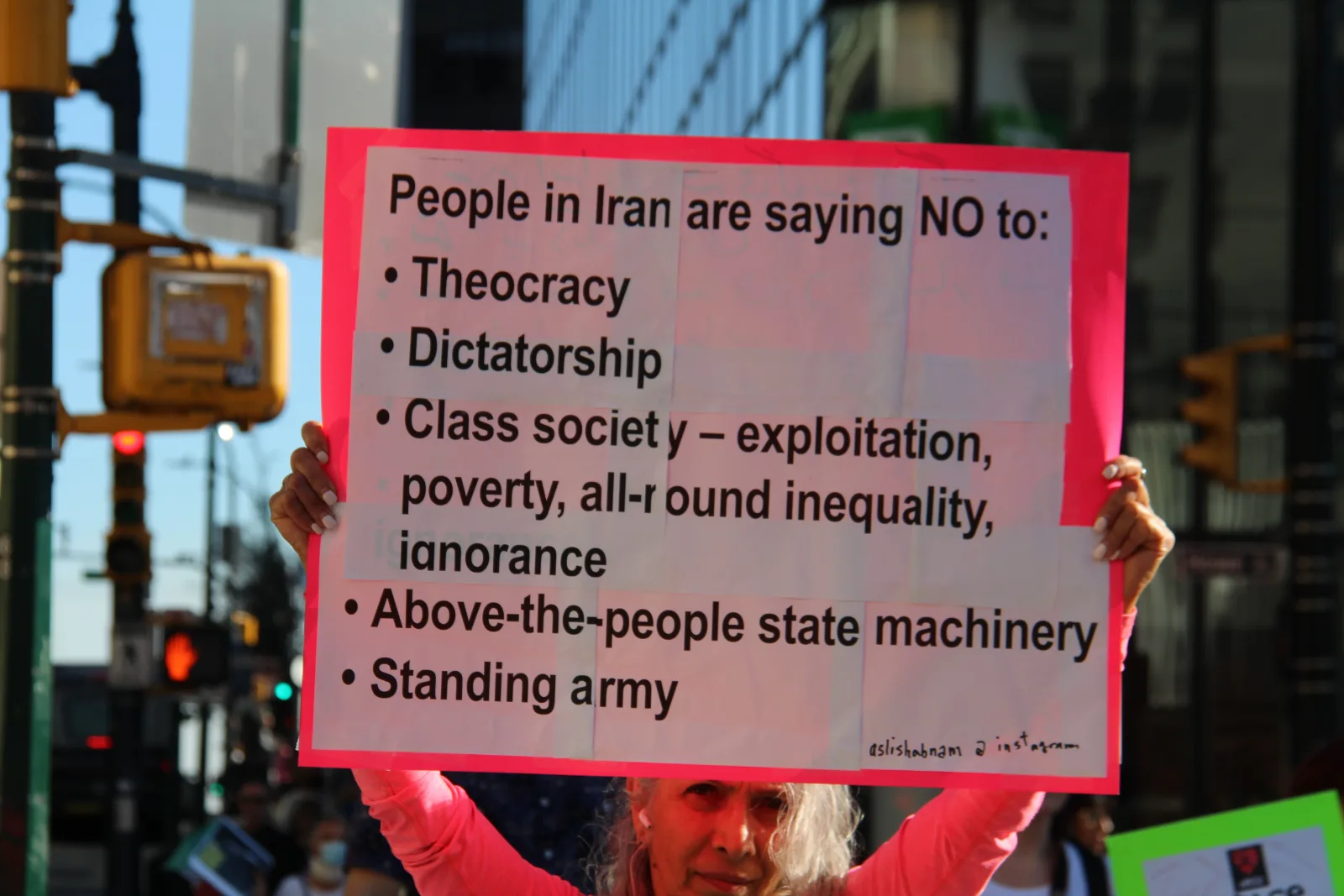 Protest in Vancouver showing support for freedom in Iran with a sign listing grievances.