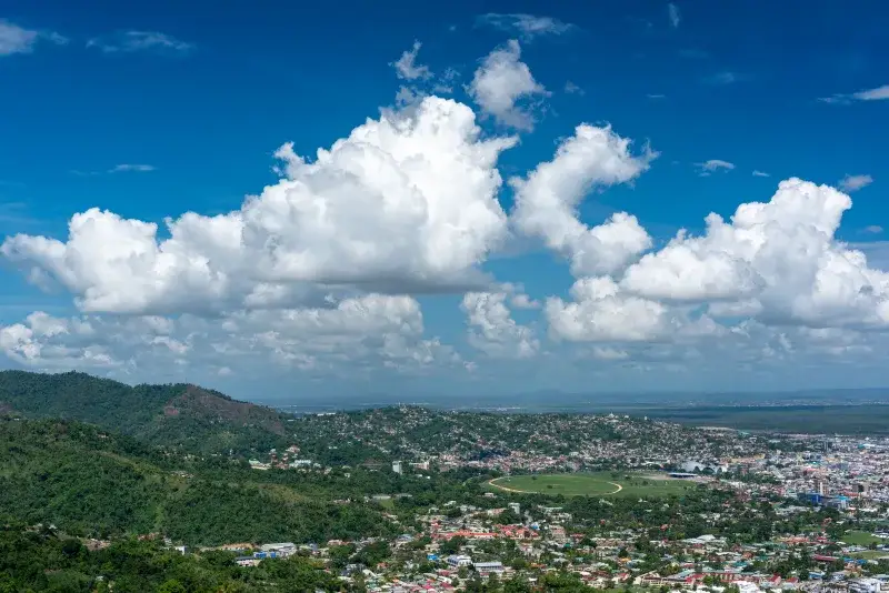 Breathtaking aerial view of Port of Spain with lush hills and clear skies, showcasing Trinidad's vibrant cityscape.