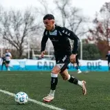 Young soccer player dribbles the ball on a grassy field during outdoor training, autumn season.
