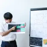 Businessman presents cryptocurrency analysis with graphs and charts on a whiteboard.