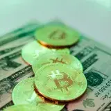 Golden Bitcoin coins placed over American dollar banknotes, highlighting crypto and cash economy.