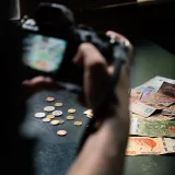 Close-up of Argentine peso notes and coins being photographed indoors.