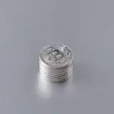 Close-up of silver Bitcoin coins stacked on a gray surface, showcasing cryptocurrency technology.