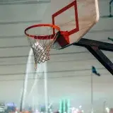 A basketball hoop set against the night skyline of Dallas, highlighting sports and urban culture.